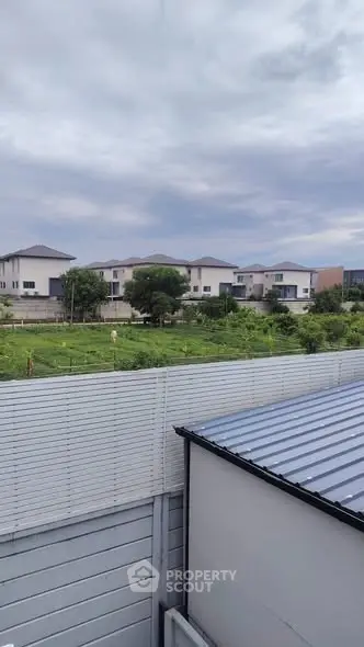 Scenic view of modern suburban homes with lush greenery and cloudy sky.