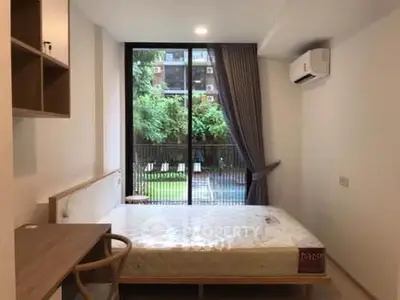 Modern bedroom with large window overlooking garden, featuring a cozy bed and air conditioning.