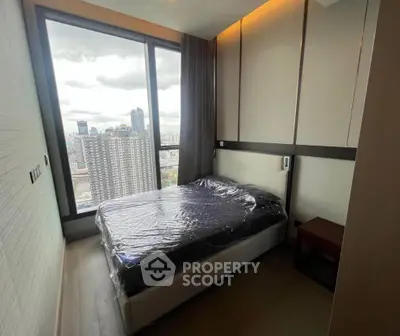 Modern bedroom with floor-to-ceiling window offering stunning city view in high-rise apartment.
