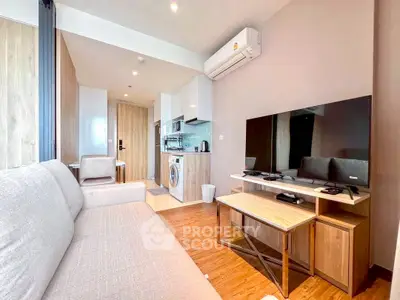 Modern living room with open kitchen, featuring sleek furniture and built-in appliances for urban living.