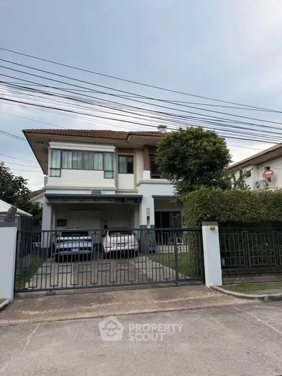 Charming two-story house with a spacious driveway and lush greenery, perfect for family living.