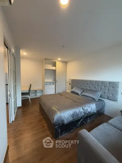 Spacious bedroom with modern decor and wooden flooring in a stylish apartment.
