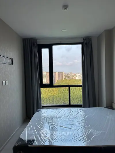 Modern bedroom with large window offering stunning city and greenery views, featuring sleek design and natural light.