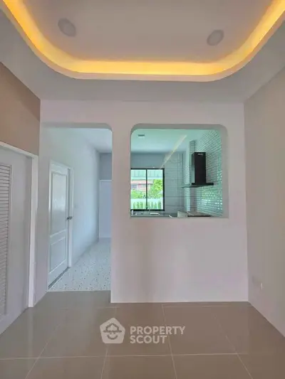 Modern kitchen with open layout and sleek design, featuring a stylish ceiling and tiled flooring.