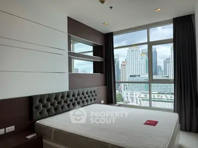 Modern bedroom with city view, featuring large windows and stylish decor in a high-rise apartment.