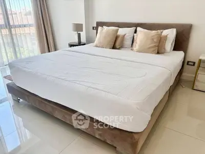 Spacious bedroom with large bed and natural light through floor-to-ceiling windows.