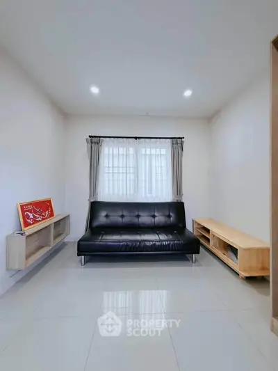 Modern minimalist living room with sleek black sofa and natural wood accents.