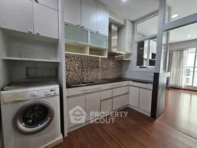 Modern kitchen with washing machine and mosaic backsplash in open layout apartment.