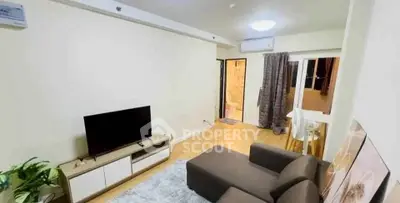 Modern living room with cozy sofa and flat-screen TV, open layout leading to dining area.
