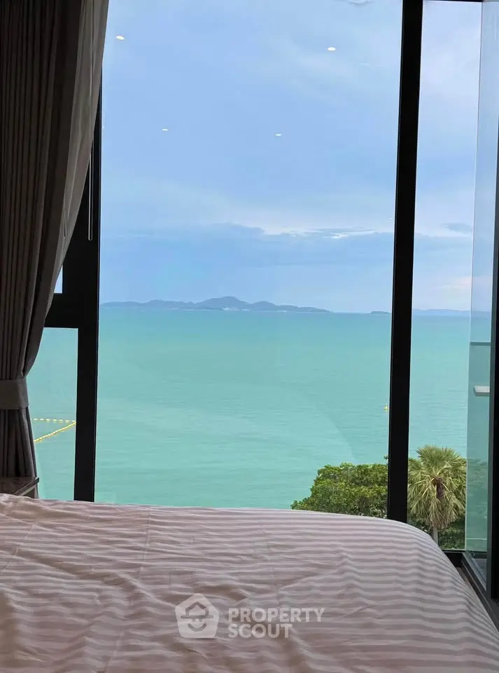 Luxurious bedroom with stunning ocean view through large windows, perfect for serene living.