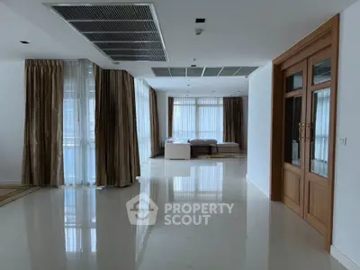 Spacious modern living area with large windows and elegant curtains in a luxury apartment.