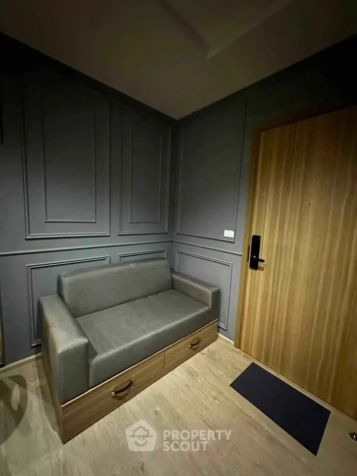 Cozy corner with modern gray sofa and wooden door in stylish apartment interior.