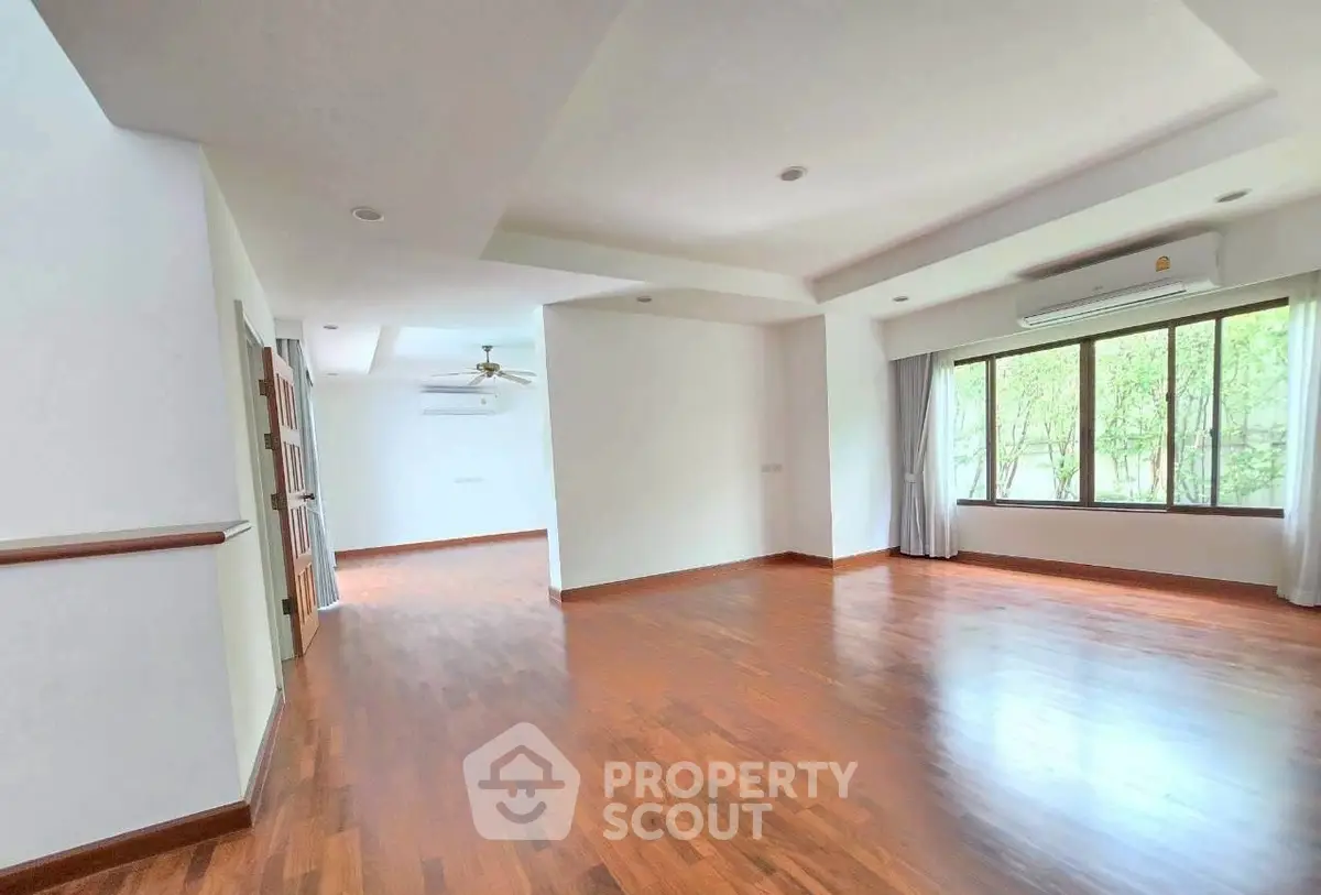 Spacious empty living room with wooden flooring and large windows