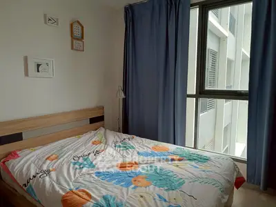 Cozy bedroom with large window and stylish decor in modern apartment.