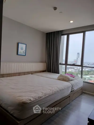 Spacious bedroom with large windows offering a stunning city view, featuring modern decor and cozy bedding.