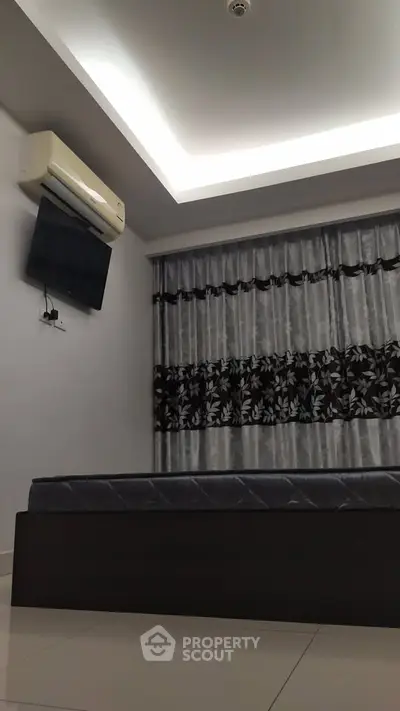 Modern bedroom with sleek design, featuring a wall-mounted TV and air conditioning.