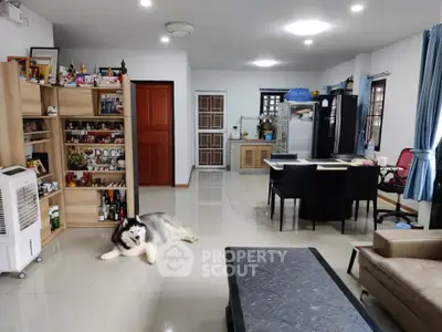 Spacious living room with modern decor and open layout, featuring a cozy seating area and stylish shelving.