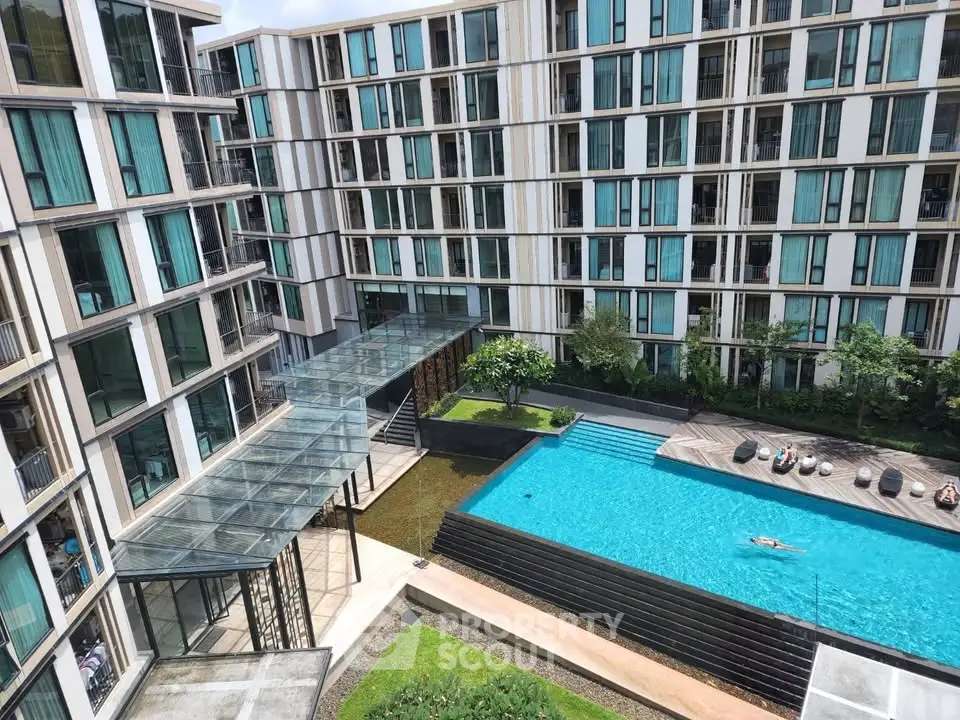 Modern apartment complex with pool and glass entrance, ideal for luxury urban living.