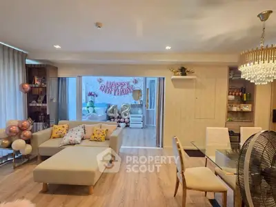 Spacious living room with elegant decor and birthday celebration setup, featuring modern furniture and a chandelier.