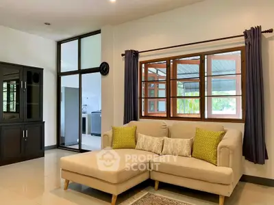 Spacious living room with modern sofa and large windows offering natural light.