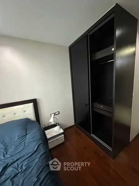 Modern bedroom with sleek dark wardrobe and elegant wooden flooring