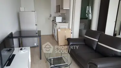 Modern apartment living room with sleek furniture and compact kitchen area.