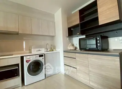 Modern kitchen with integrated washing machine and sleek wooden cabinets.