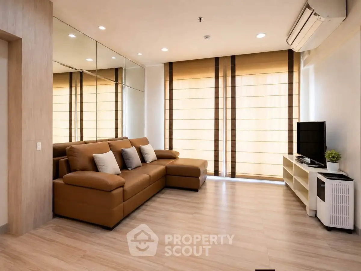 Modern living room with sleek design, featuring a large leather sofa, flat-screen TV, and floor-to-ceiling windows.