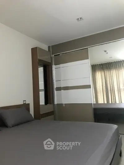 Modern bedroom with sleek design and large mirrored wardrobe in a stylish apartment.