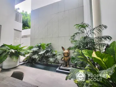 Serene indoor garden oasis with lush greenery and artistic bunny sculpture, creating a tranquil urban retreat in a modern home.