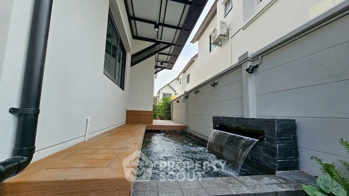 Modern home exterior with sleek water feature and wooden deck