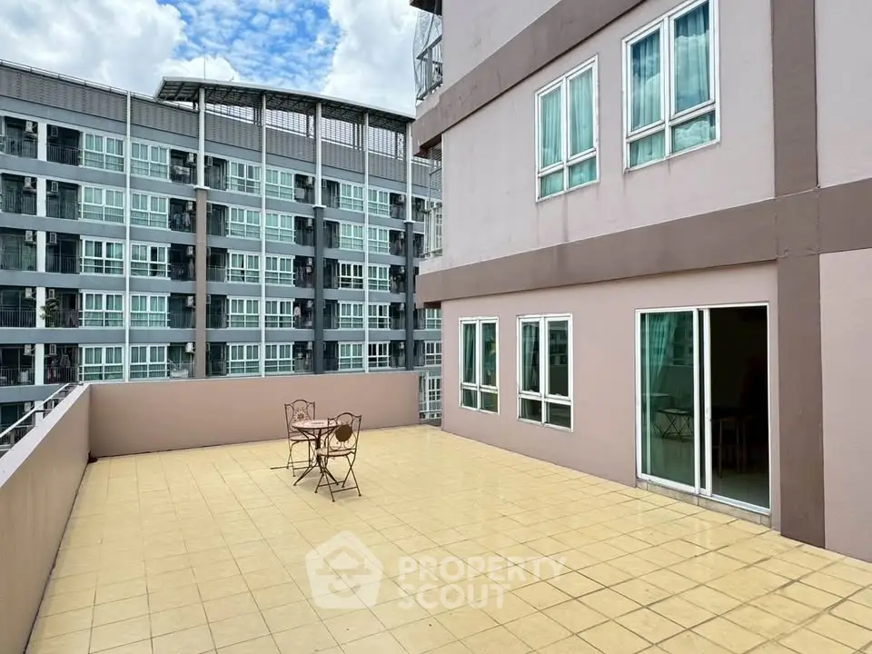 Spacious balcony with outdoor seating and city view in modern apartment complex.