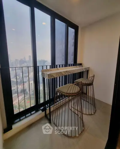 Stylish balcony with city view, featuring modern bar stools and sleek design.