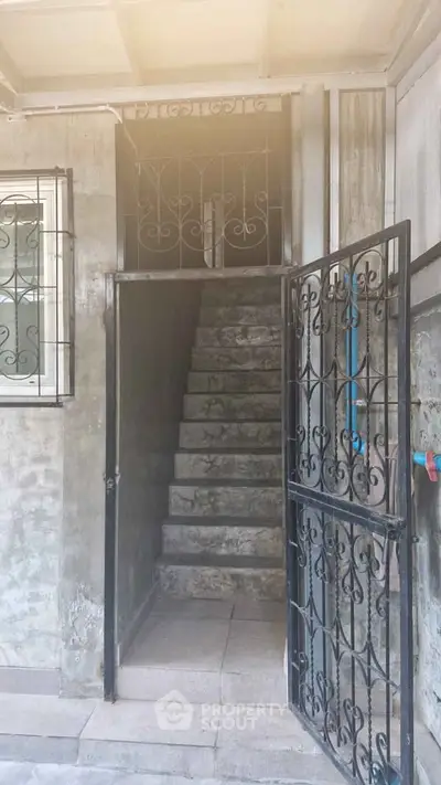 Charming entrance with wrought iron gate and stone staircase, perfect for a cozy home.