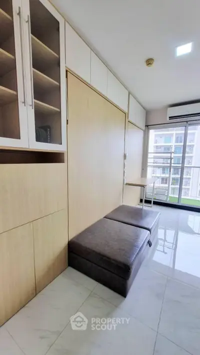 Modern apartment interior with built-in storage and large windows offering city views.