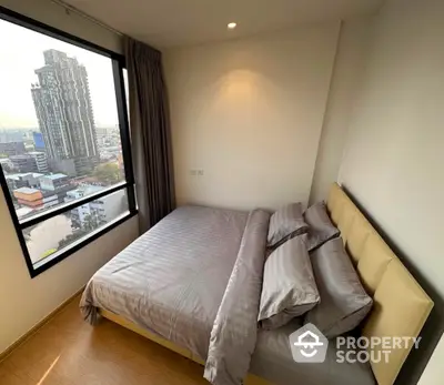 Modern bedroom with city view and large window in high-rise apartment