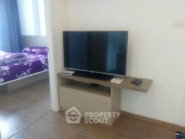 Modern living room with sleek TV setup and glimpse of cozy bedroom