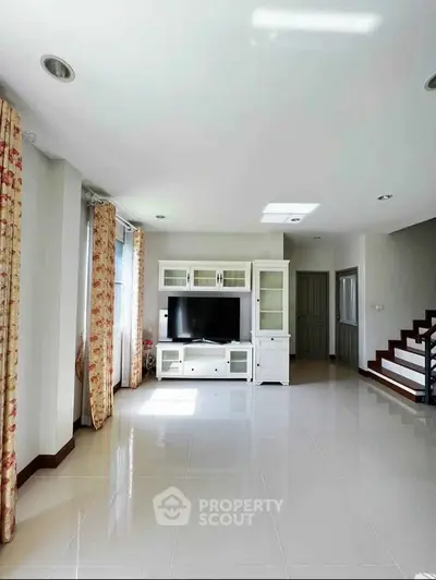 Spacious living room with modern TV unit and elegant curtains, perfect for family gatherings.