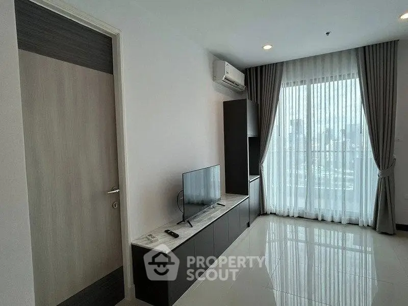 Modern living room with sleek TV unit and city view through large window.