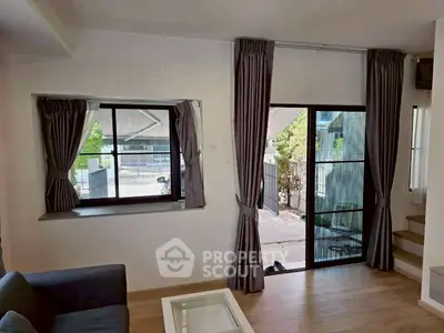 Bright living room with large windows and modern decor, featuring a view of the outdoor area.