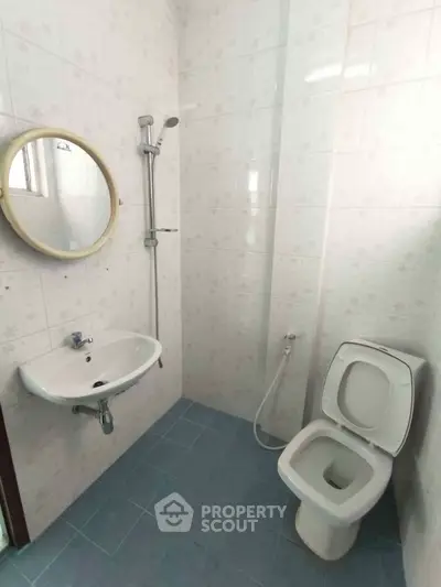 Compact bathroom with shower, sink, and toilet in tiled interior.