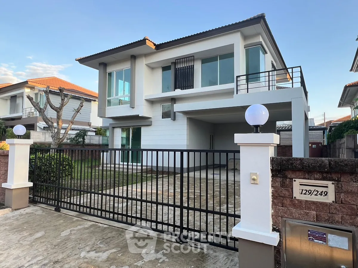 Modern two-story house with gated entrance and spacious driveway in a suburban neighborhood.