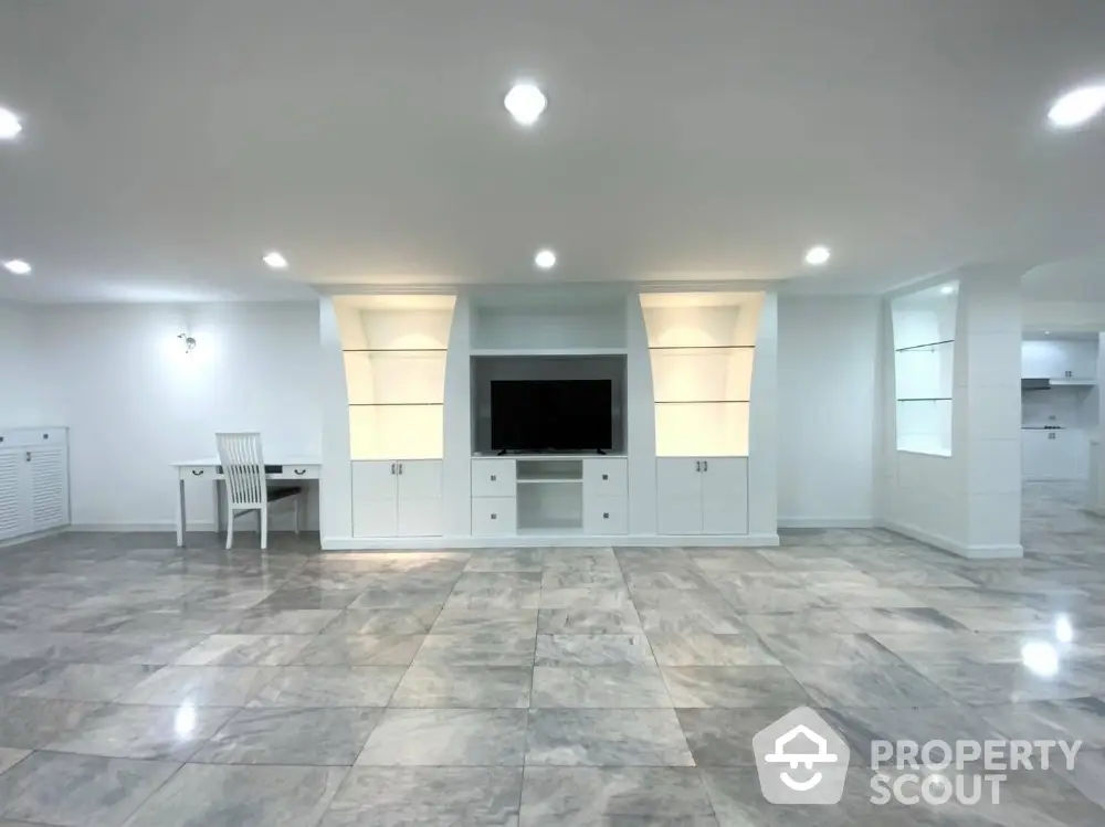 Spacious modern living room with elegant marble flooring and built-in entertainment center.