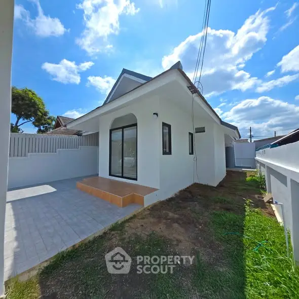 Charming single-story home with spacious yard and modern design under a bright blue sky.