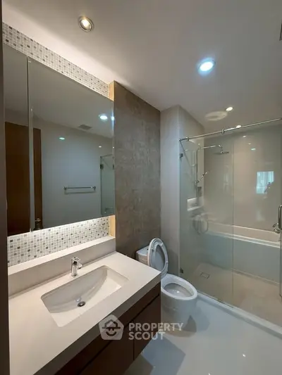 Modern bathroom with glass shower and sleek vanity in luxury apartment