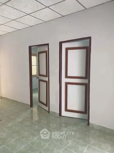 Spacious interior with tiled floor and two wooden doors, ideal for versatile use.
