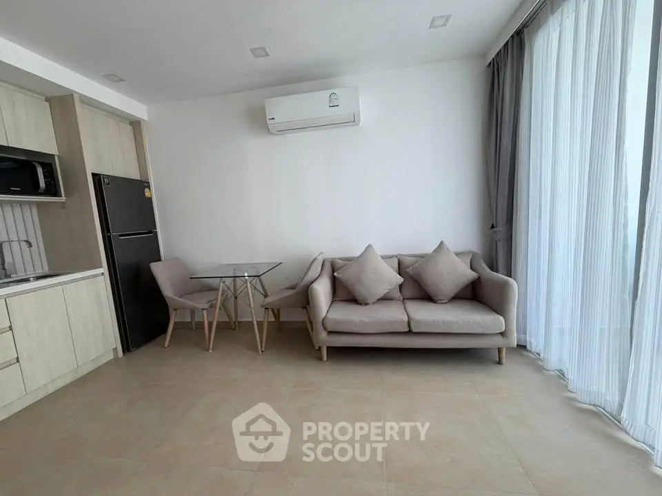 Modern living room with sleek furniture and open kitchen layout in a bright apartment.