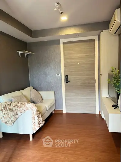 Cozy living room with modern decor and wooden flooring, featuring a comfortable sofa and stylish lighting.