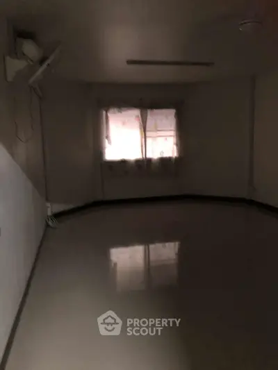 Dimly lit empty room with reflective floor and curtained window.