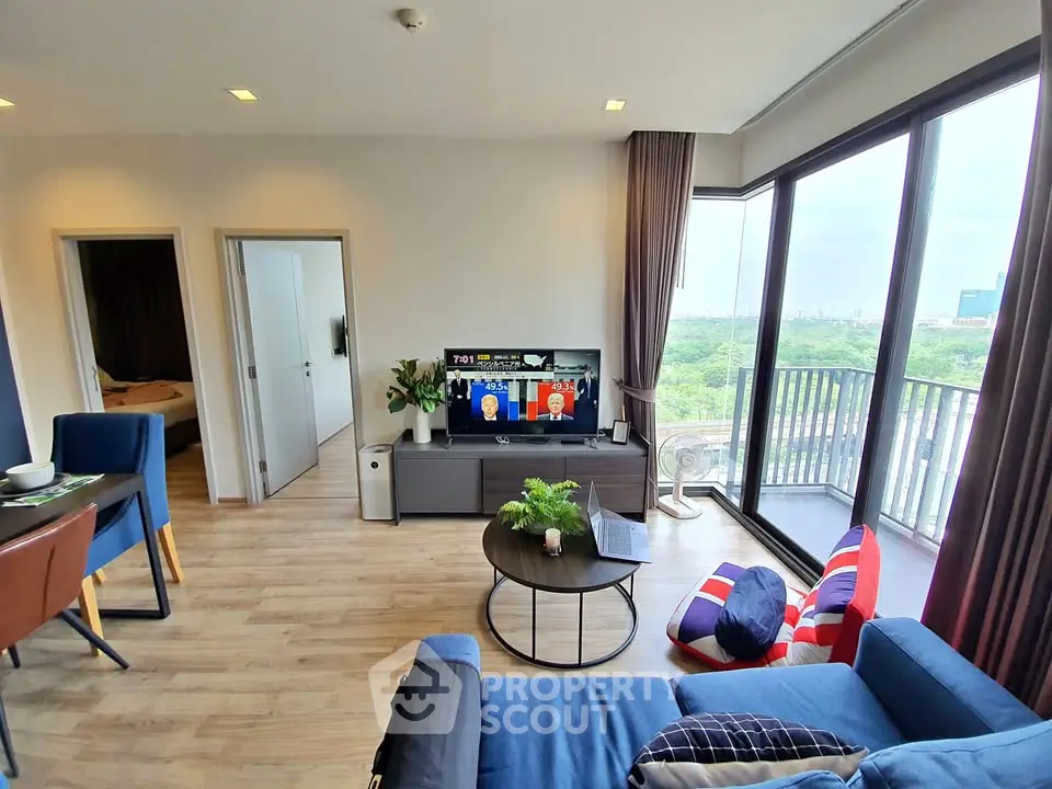 Modern living room with large windows and balcony offering a stunning view, featuring stylish furniture and decor.